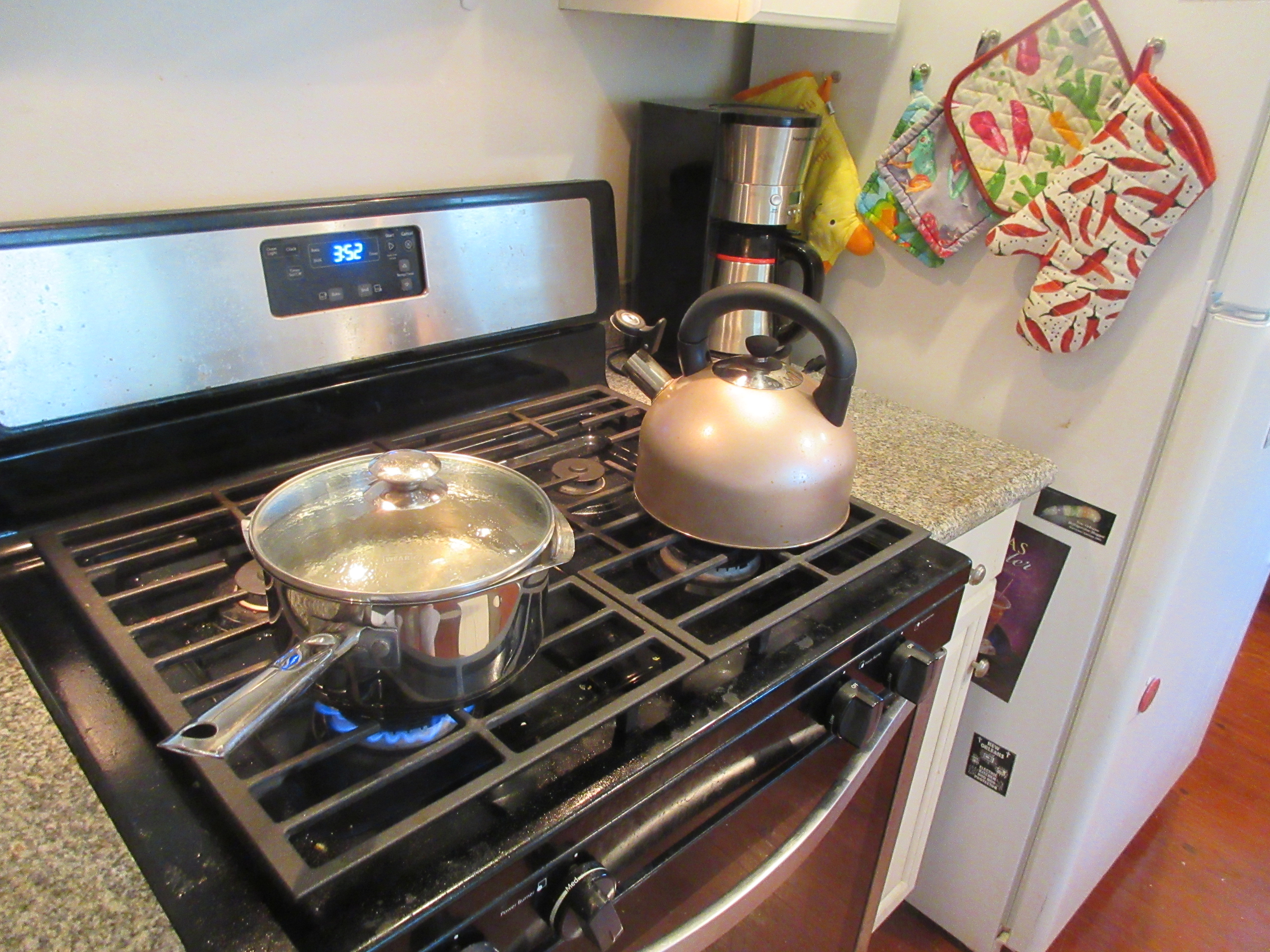 Covered saucepan and kettle on a gas range in a home kitchen