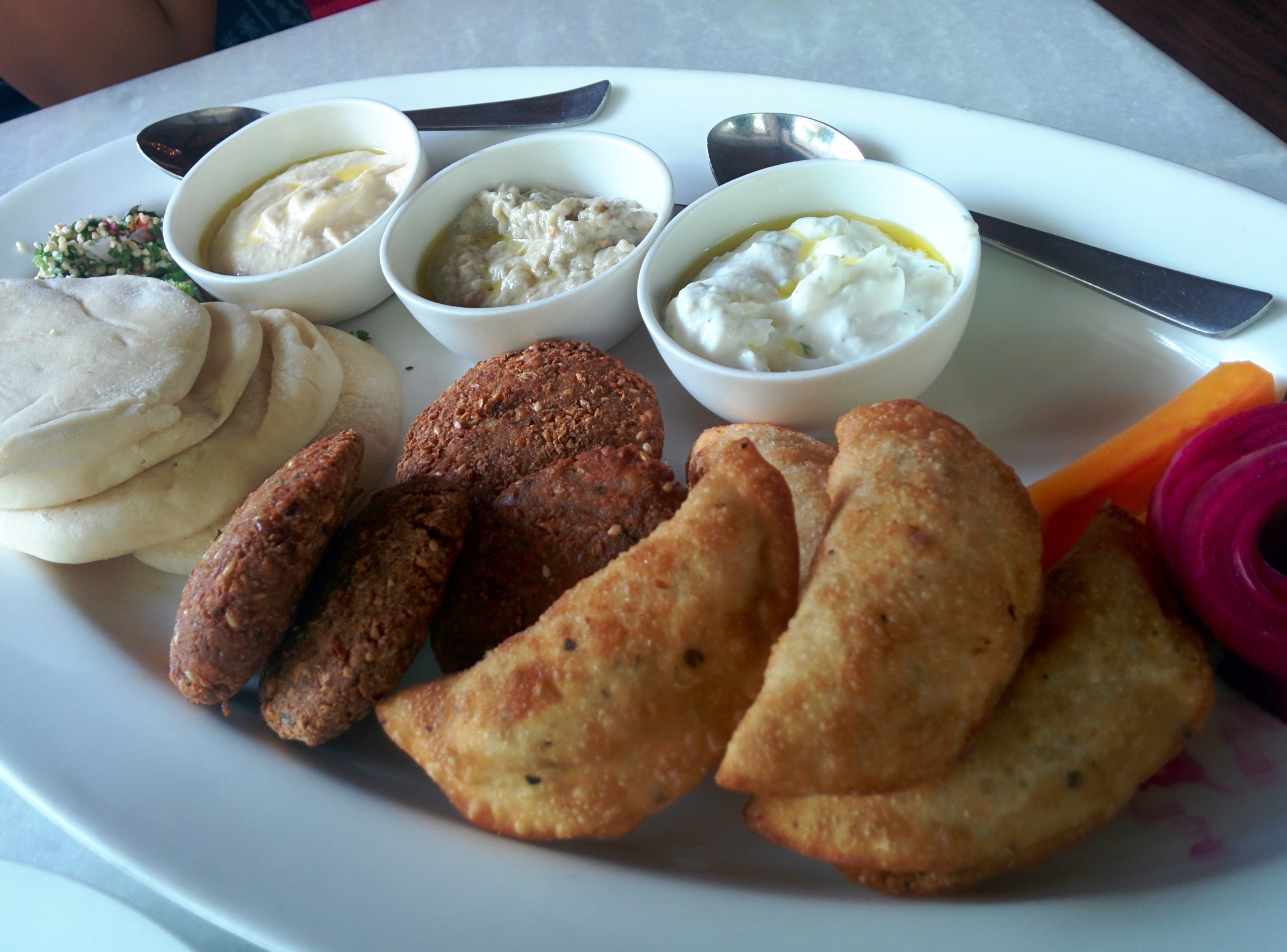 Mezze platter with falafel, pastries, pita and three dips in small bowls
