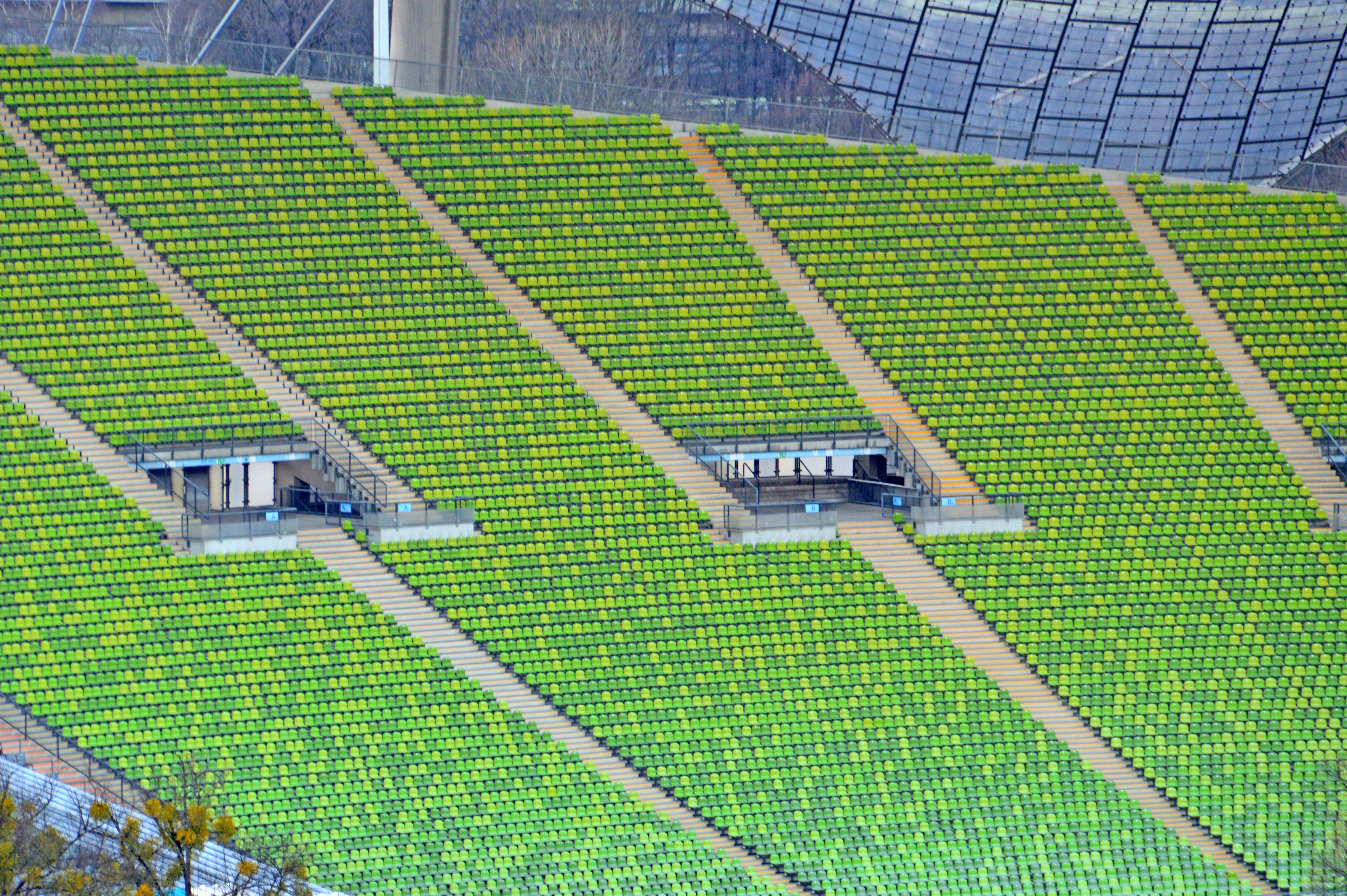 Rows of empty green seats rising up the stands of a large stadium