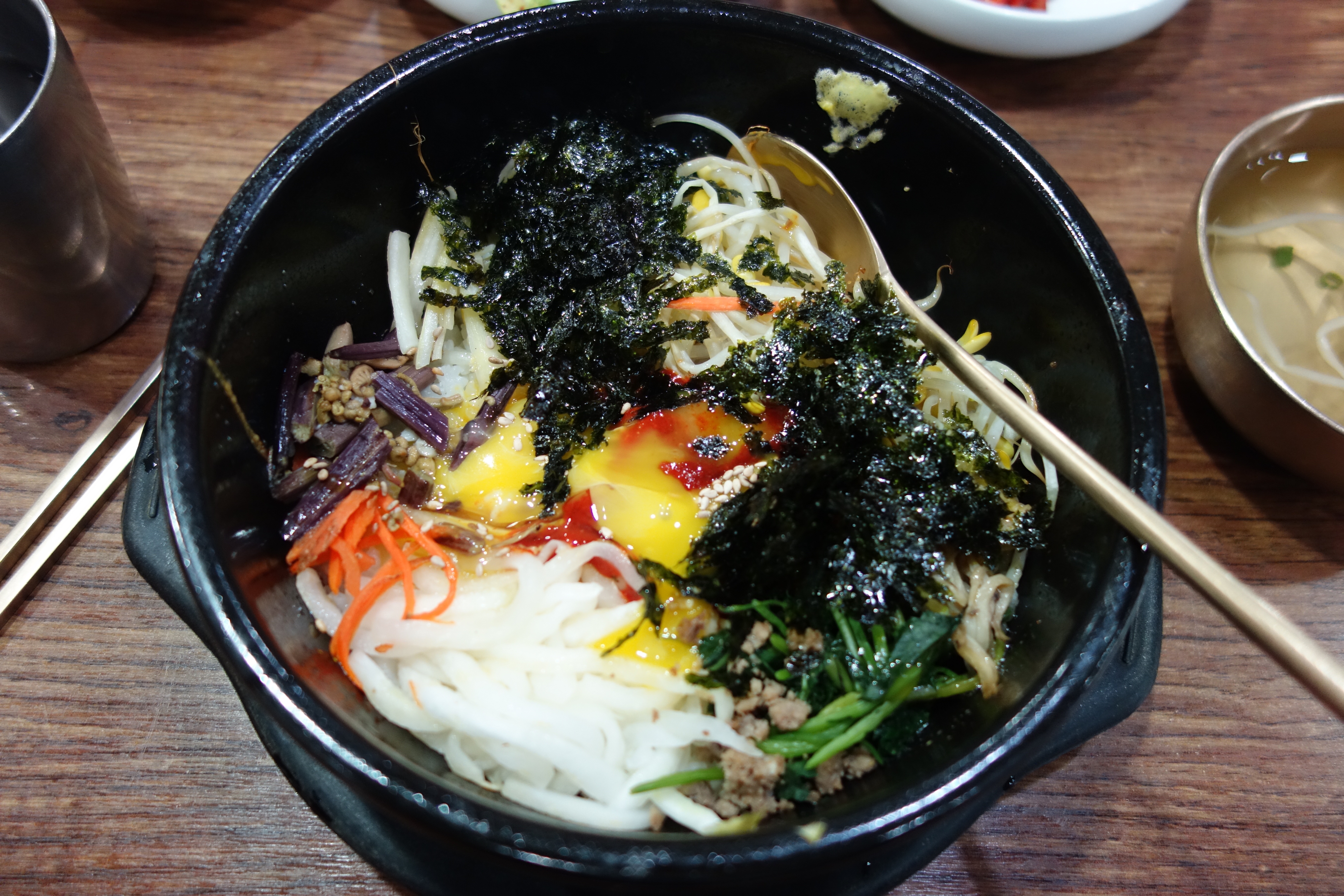 Bibimbap in a hot stone bowl with vegetables, egg and seaweed