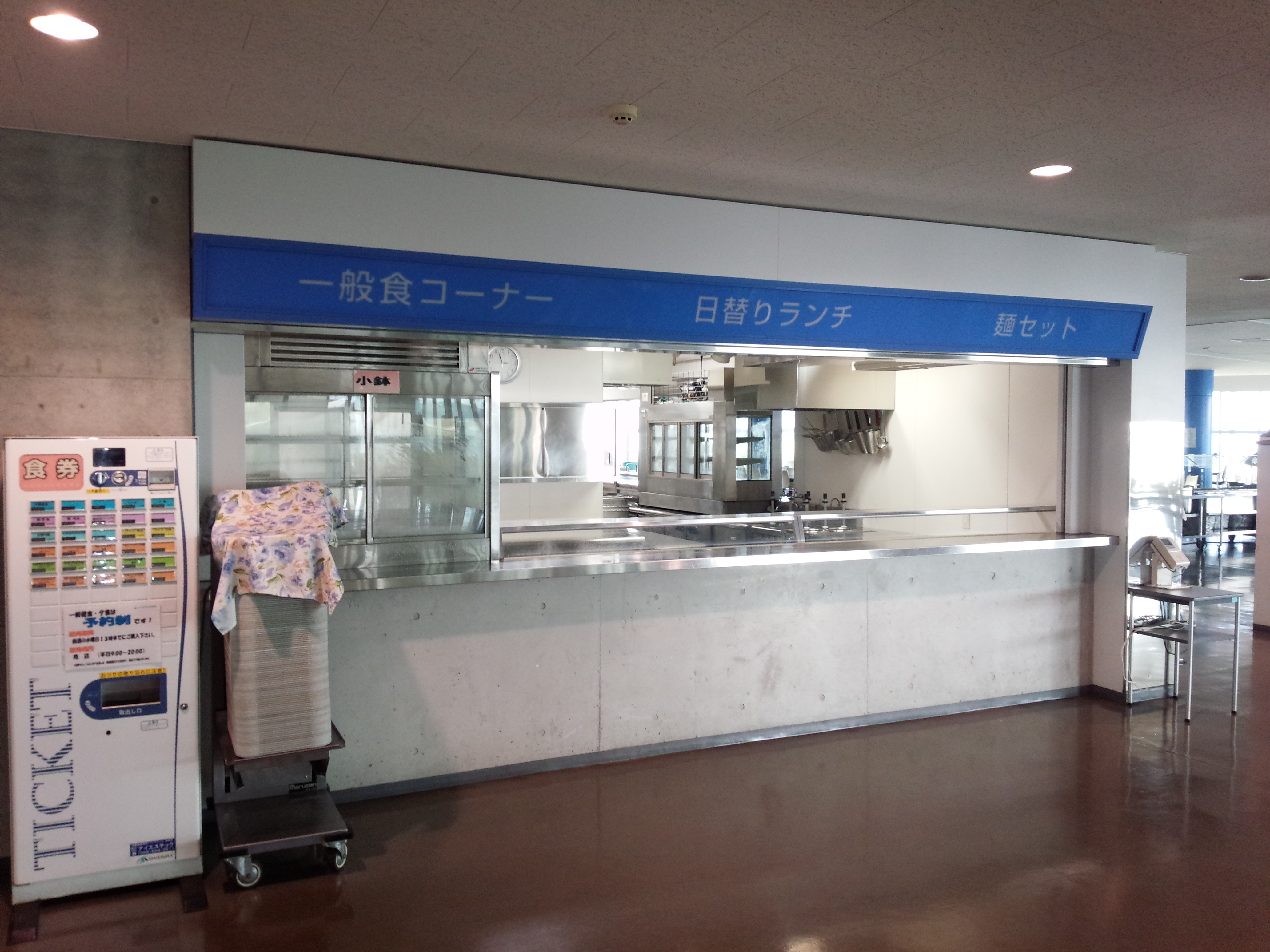 Quiet campus cafeteria serving counter with a meal ticket machine beside it