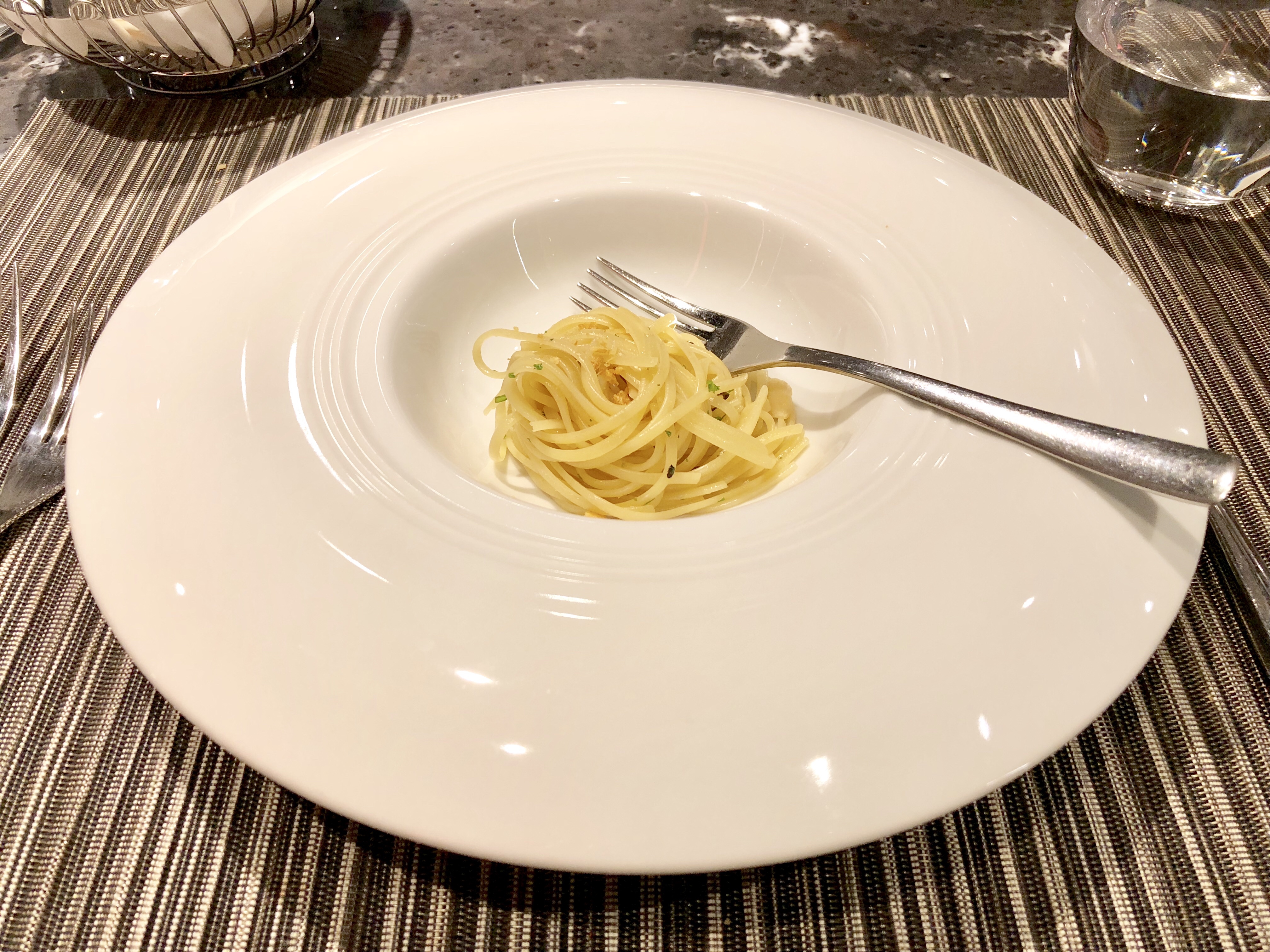 Small serving of spaghetti in a wide white bowl on a restaurant table