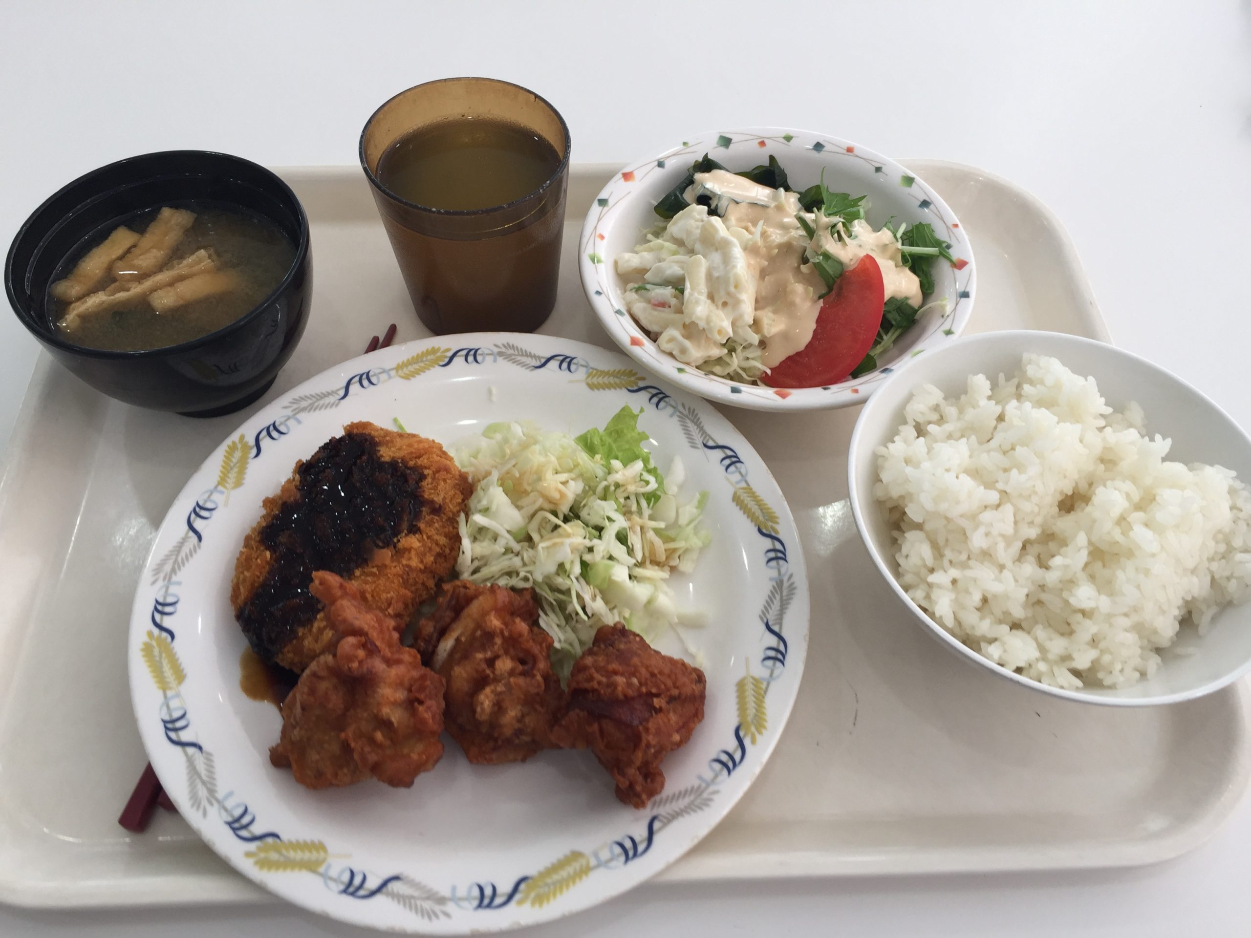 Cafeteria tray with fried chicken, a croquette, shredded cabbage, rice, miso soup and salad