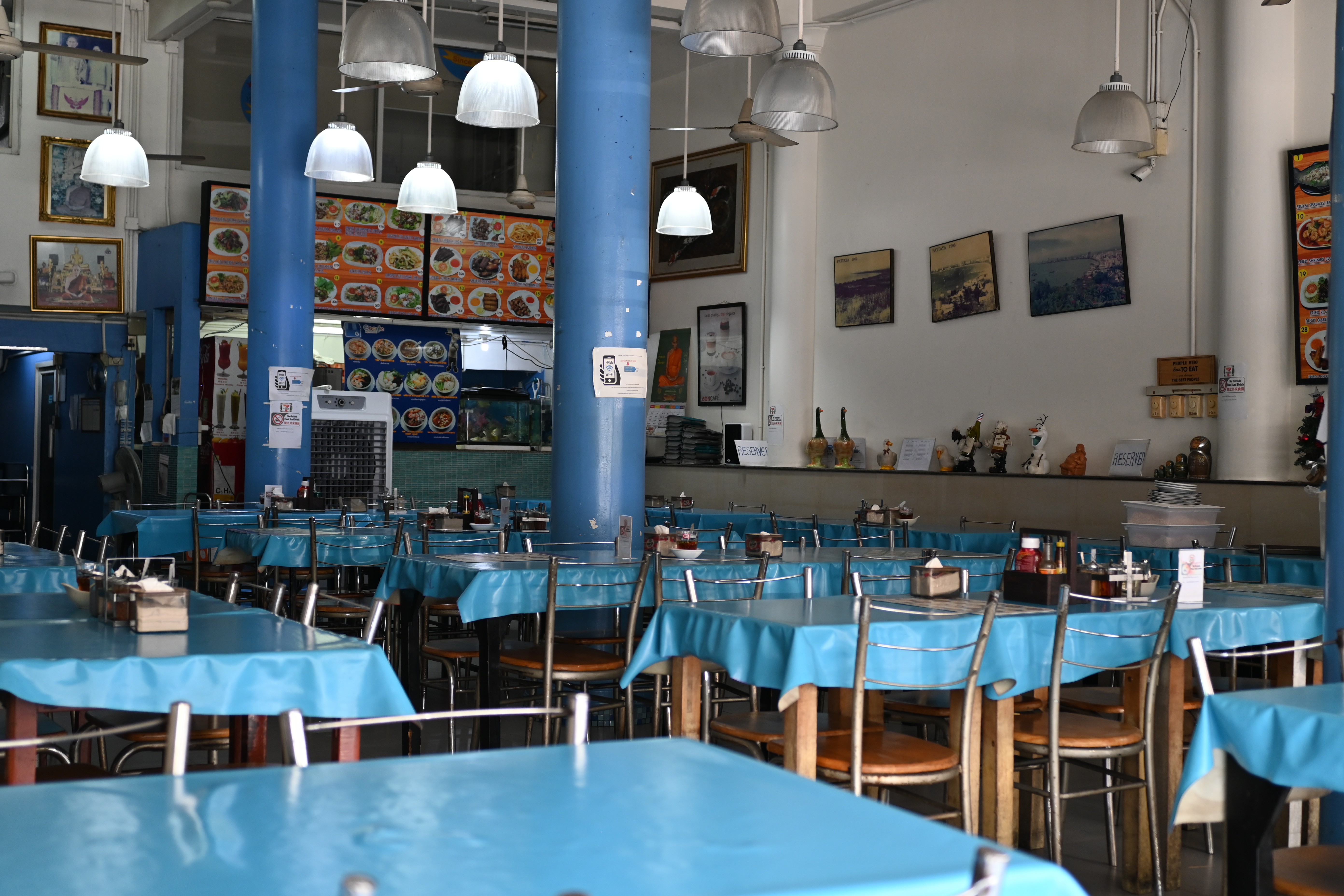 Empty casual restaurant with blue tablecloths, pendant lights and photo menus above the counter
