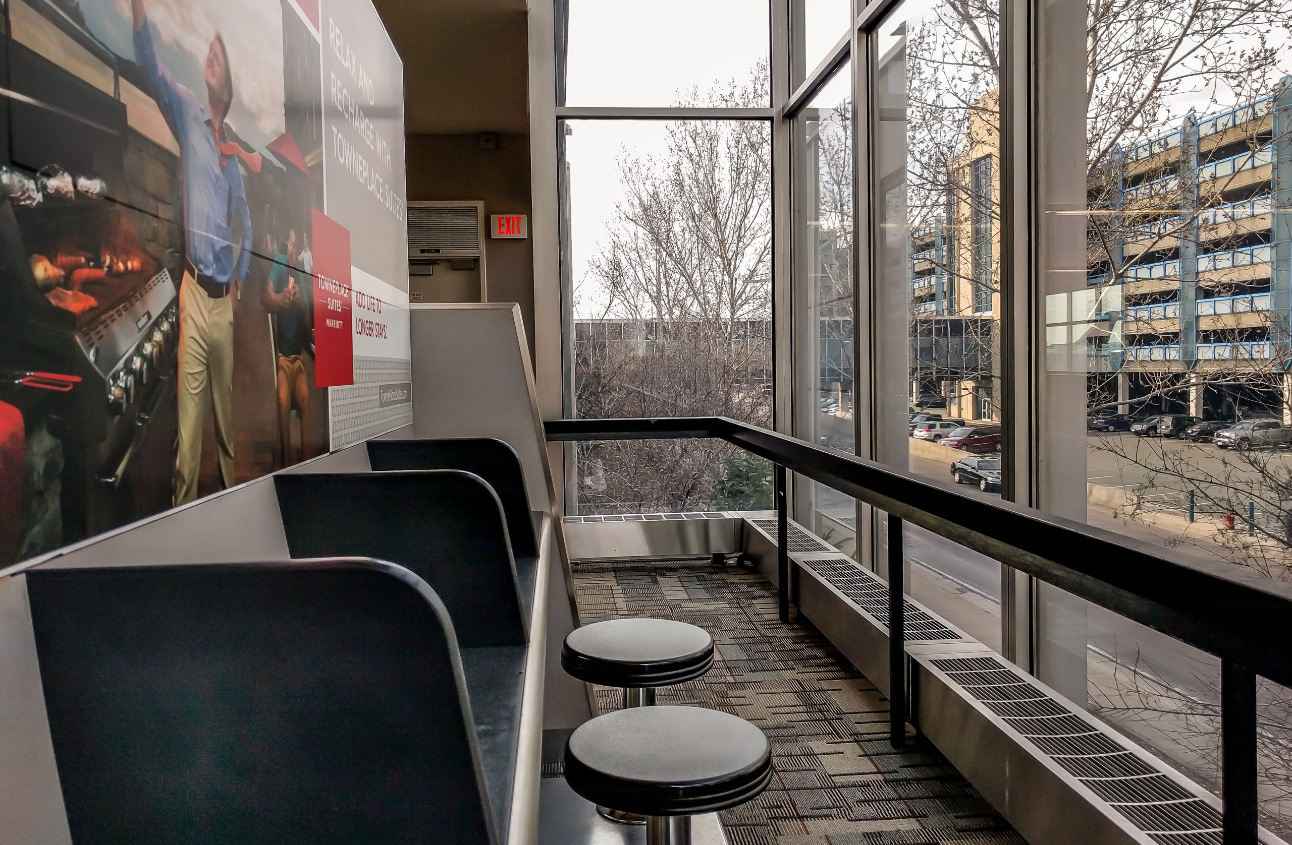 Empty counter seating with stools beside large windows in an airport terminal